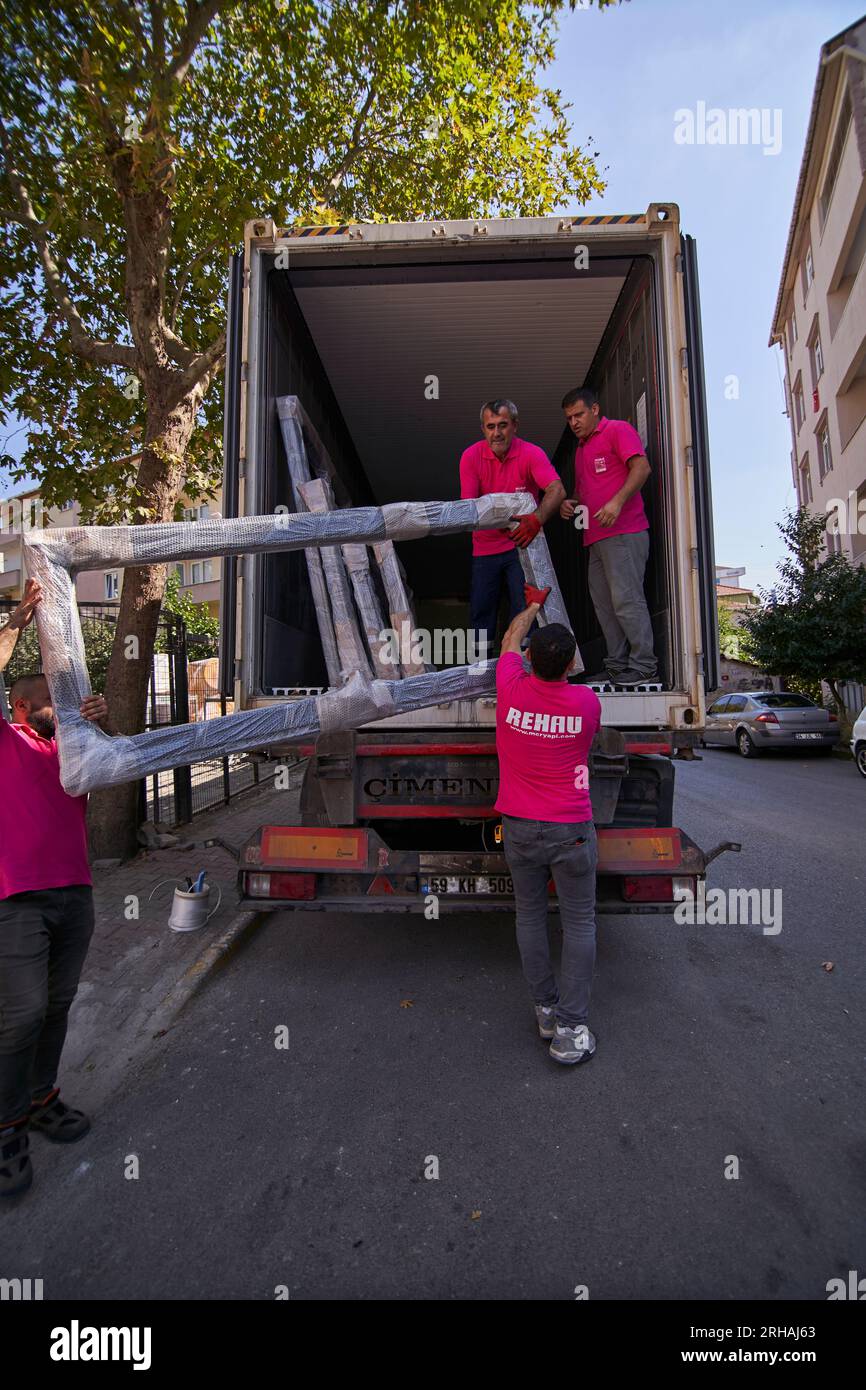 Lavoratori che confezionano fogli di vetro in magazzino. lavoratore che spedisce la finestra in vetro. lavoratore che indossa giubbotto di sicurezza e casco. Foto Stock