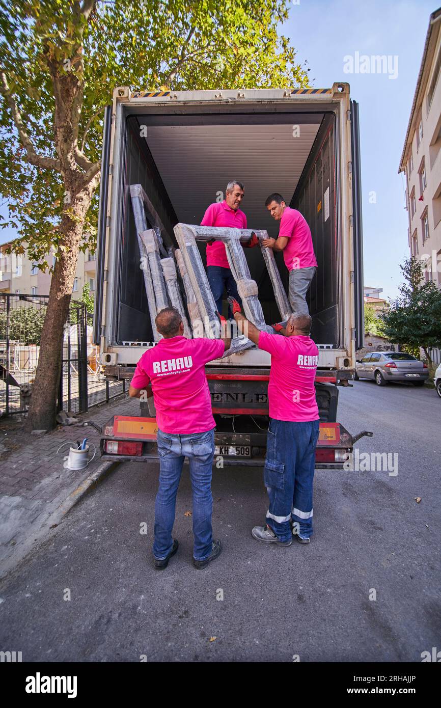 Lavoratori che confezionano fogli di vetro in magazzino. lavoratore che spedisce la finestra in vetro. lavoratore che indossa giubbotto di sicurezza e casco. Foto Stock