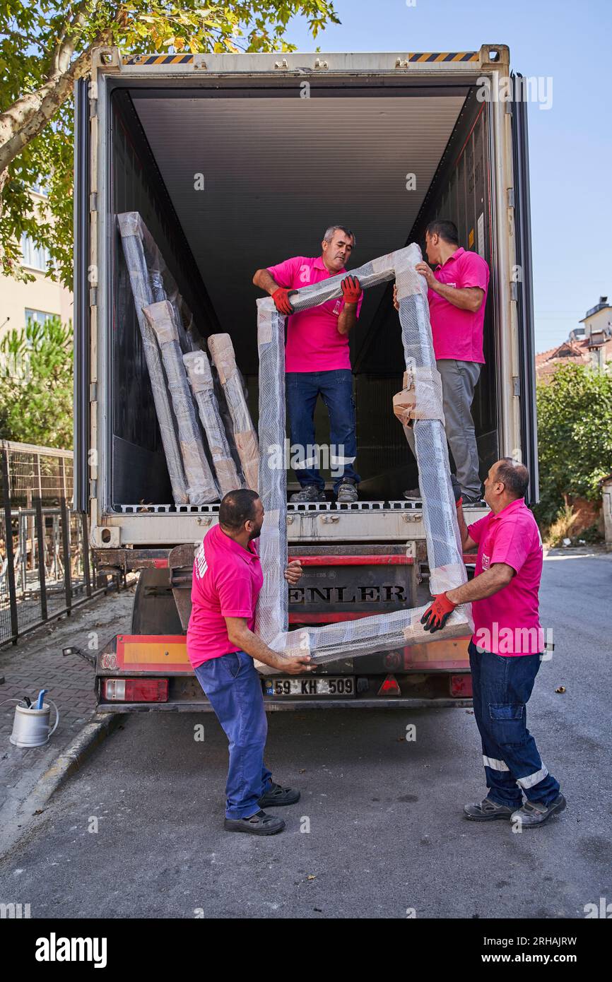 Lavoratori che confezionano fogli di vetro in magazzino. lavoratore che spedisce la finestra in vetro. lavoratore che indossa giubbotto di sicurezza e casco. Foto Stock