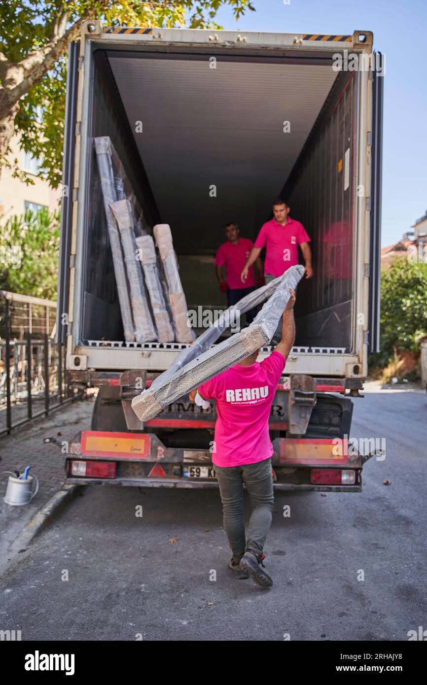 Lavoratori che confezionano fogli di vetro in magazzino. lavoratore che spedisce la finestra in vetro. lavoratore che indossa giubbotto di sicurezza e casco. Foto Stock