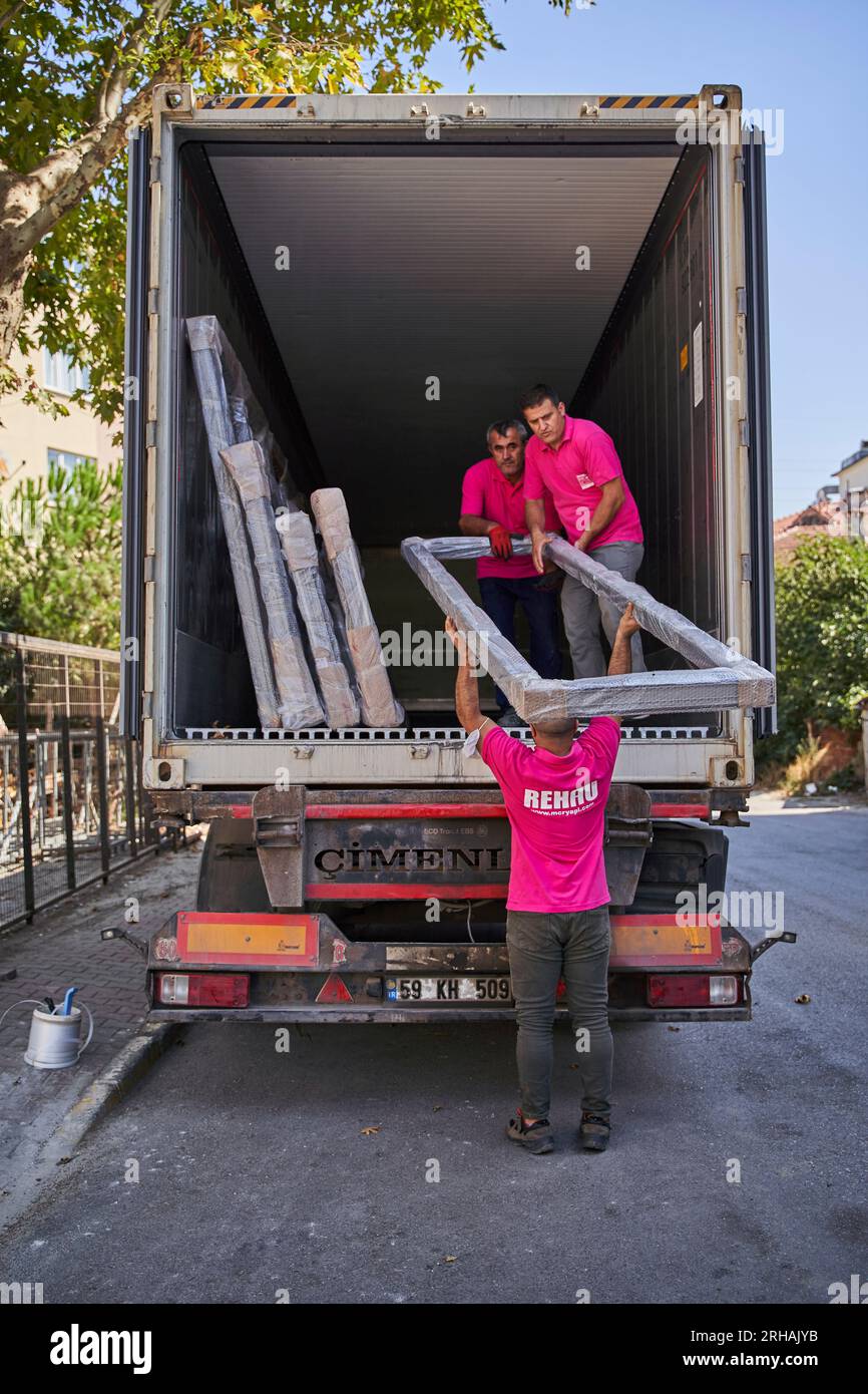 Lavoratori che confezionano fogli di vetro in magazzino. lavoratore che spedisce la finestra in vetro. lavoratore che indossa giubbotto di sicurezza e casco. Foto Stock