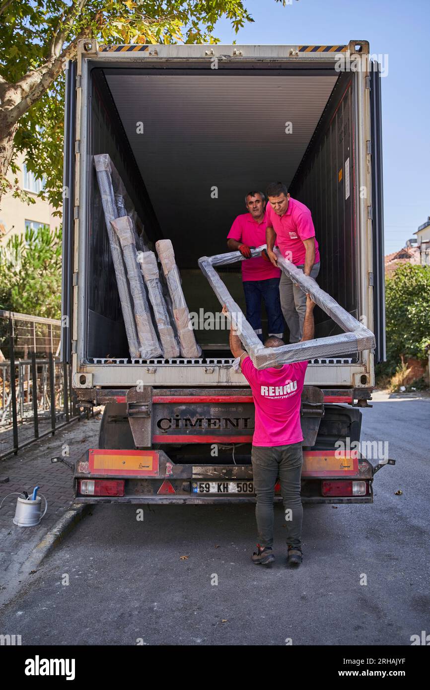 Lavoratori che confezionano fogli di vetro in magazzino. lavoratore che spedisce la finestra in vetro. lavoratore che indossa giubbotto di sicurezza e casco. Foto Stock