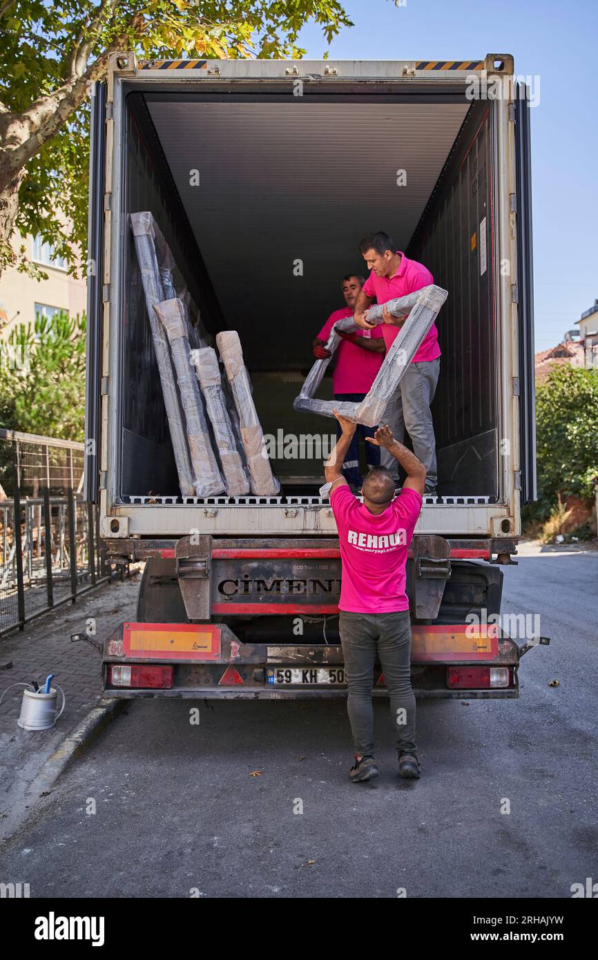 Lavoratori che confezionano fogli di vetro in magazzino. lavoratore che spedisce la finestra in vetro. lavoratore che indossa giubbotto di sicurezza e casco. Foto Stock