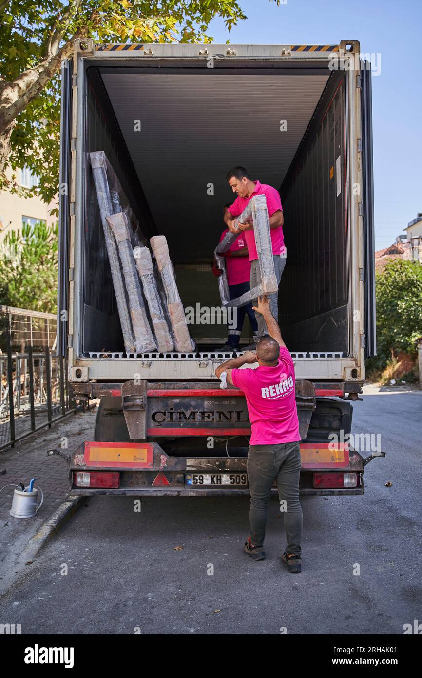 Lavoratori che confezionano fogli di vetro in magazzino. lavoratore che spedisce la finestra in vetro. lavoratore che indossa giubbotto di sicurezza e casco. Foto Stock