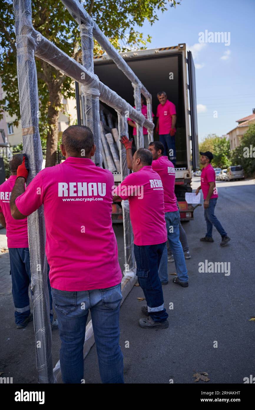 Lavoratori che confezionano fogli di vetro in magazzino. lavoratore che spedisce la finestra in vetro. lavoratore che indossa giubbotto di sicurezza e casco. Foto Stock