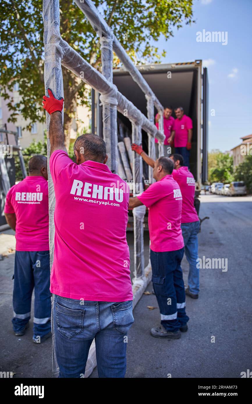Lavoratori che confezionano fogli di vetro in magazzino. lavoratore che spedisce la finestra in vetro. lavoratore che indossa giubbotto di sicurezza e casco. Foto Stock