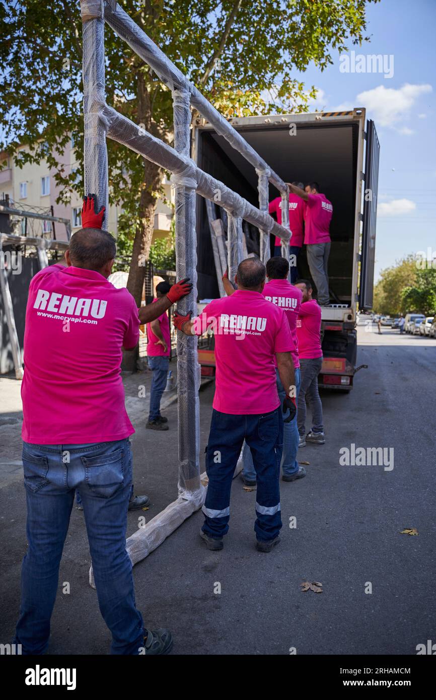 Lavoratori che confezionano fogli di vetro in magazzino. lavoratore che spedisce la finestra in vetro. lavoratore che indossa giubbotto di sicurezza e casco. Foto Stock