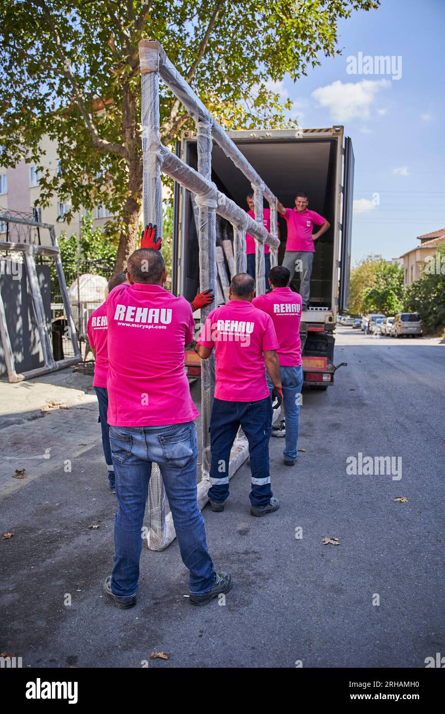 Lavoratori che confezionano fogli di vetro in magazzino. lavoratore che spedisce la finestra in vetro. lavoratore che indossa giubbotto di sicurezza e casco. Foto Stock