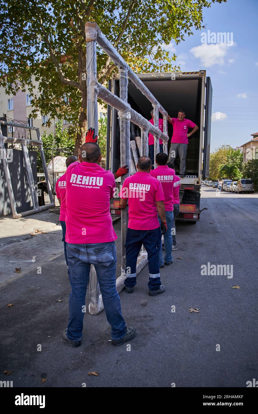 Lavoratori che confezionano fogli di vetro in magazzino. lavoratore che spedisce la finestra in vetro. lavoratore che indossa giubbotto di sicurezza e casco. Foto Stock