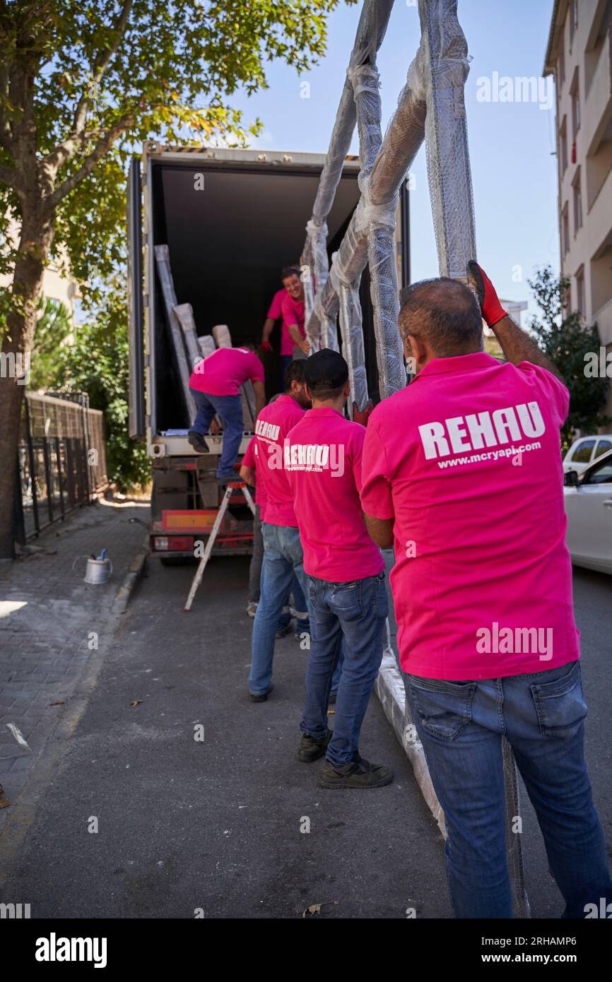Lavoratori che confezionano fogli di vetro in magazzino. lavoratore che spedisce la finestra in vetro. lavoratore che indossa giubbotto di sicurezza e casco. Foto Stock