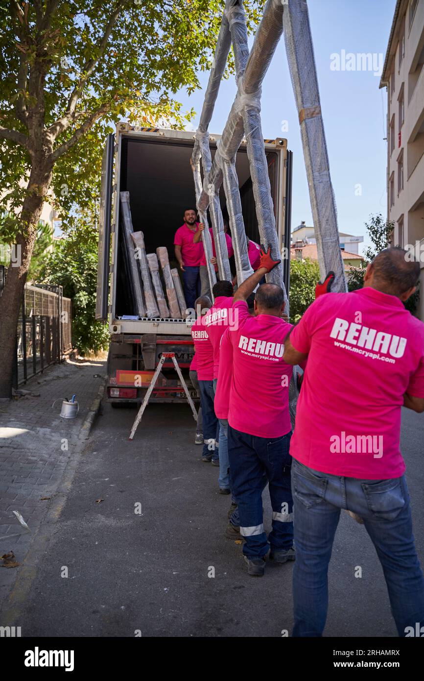 Lavoratori che confezionano fogli di vetro in magazzino. lavoratore che spedisce la finestra in vetro. lavoratore che indossa giubbotto di sicurezza e casco. Foto Stock