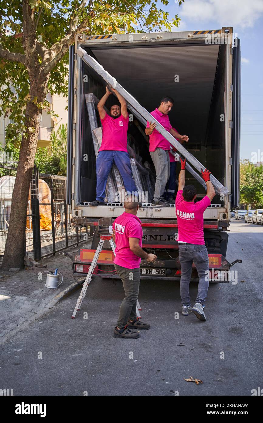 Lavoratori che confezionano fogli di vetro in magazzino. lavoratore che spedisce la finestra in vetro. lavoratore che indossa giubbotto di sicurezza e casco. Foto Stock