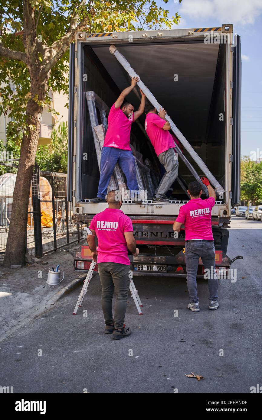 Lavoratori che confezionano fogli di vetro in magazzino. lavoratore che spedisce la finestra in vetro. lavoratore che indossa giubbotto di sicurezza e casco. Foto Stock