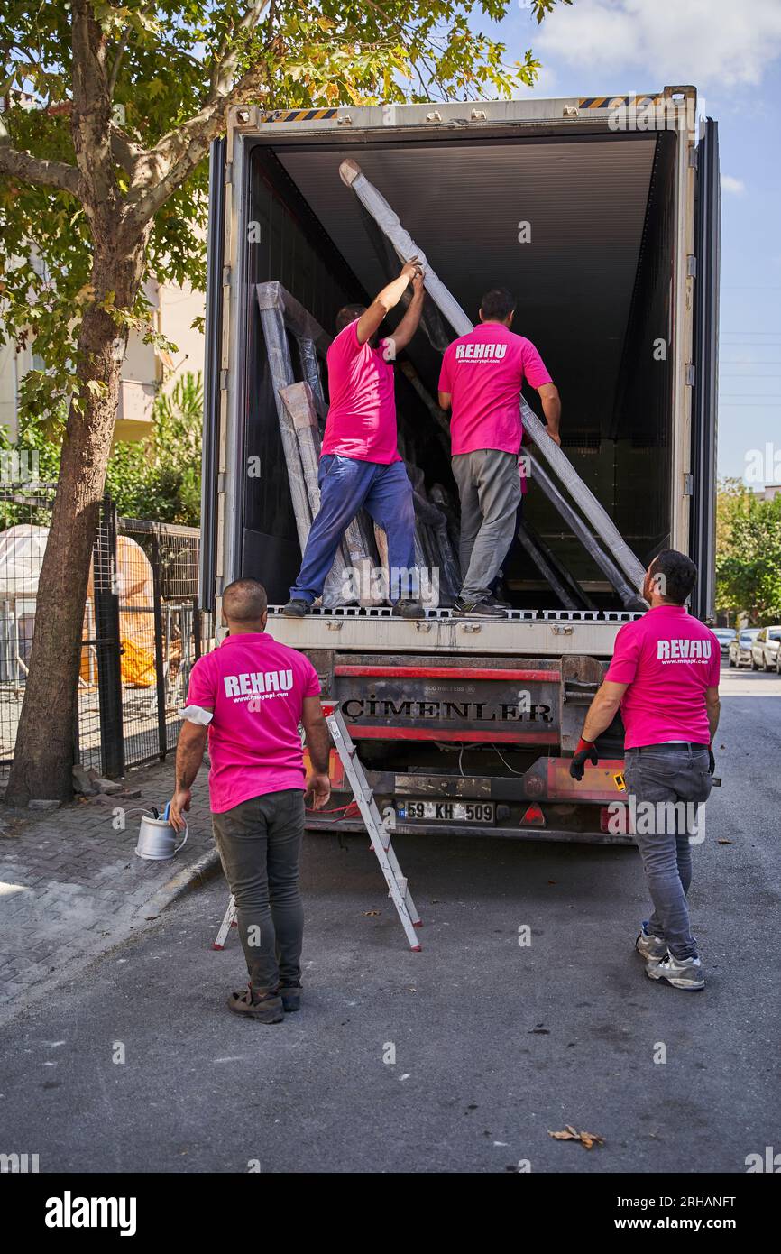 Lavoratori che confezionano fogli di vetro in magazzino. lavoratore che spedisce la finestra in vetro. lavoratore che indossa giubbotto di sicurezza e casco. Foto Stock