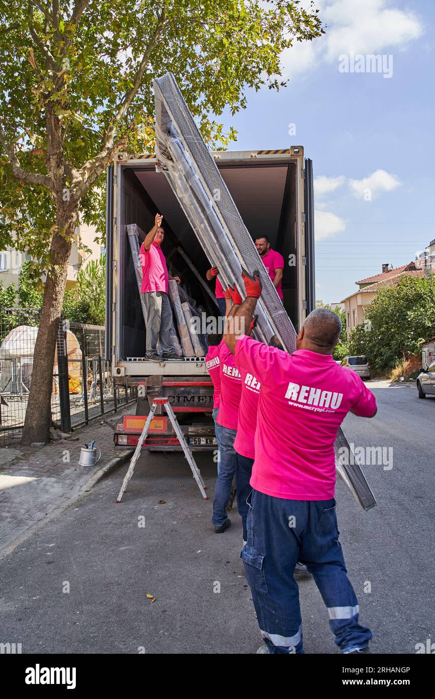 Lavoratori che confezionano fogli di vetro in magazzino. lavoratore che spedisce la finestra in vetro. lavoratore che indossa giubbotto di sicurezza e casco. Foto Stock