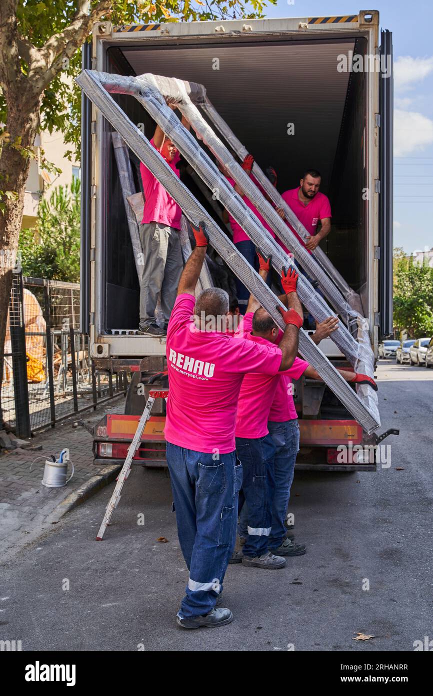 Lavoratori che confezionano fogli di vetro in magazzino. lavoratore che spedisce la finestra in vetro. lavoratore che indossa giubbotto di sicurezza e casco. Foto Stock