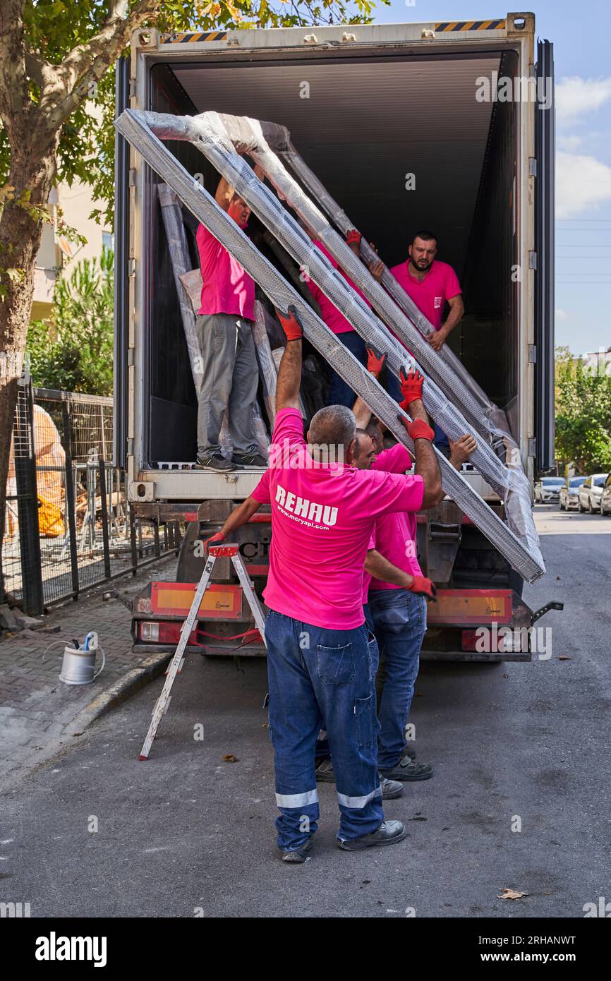 Lavoratori che confezionano fogli di vetro in magazzino. lavoratore che spedisce la finestra in vetro. lavoratore che indossa giubbotto di sicurezza e casco. Foto Stock