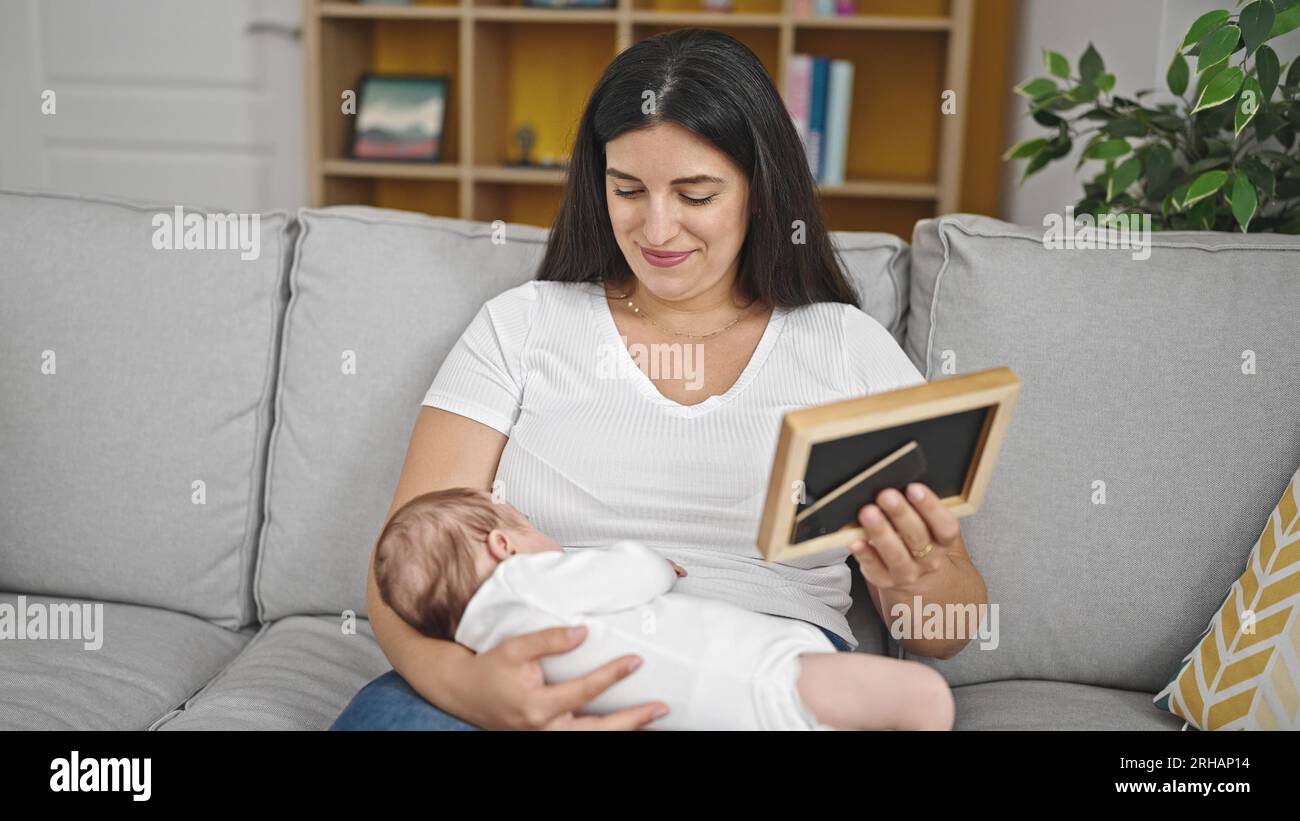 Madre e bambina seduti sul divano guardando la cornice di casa Foto Stock