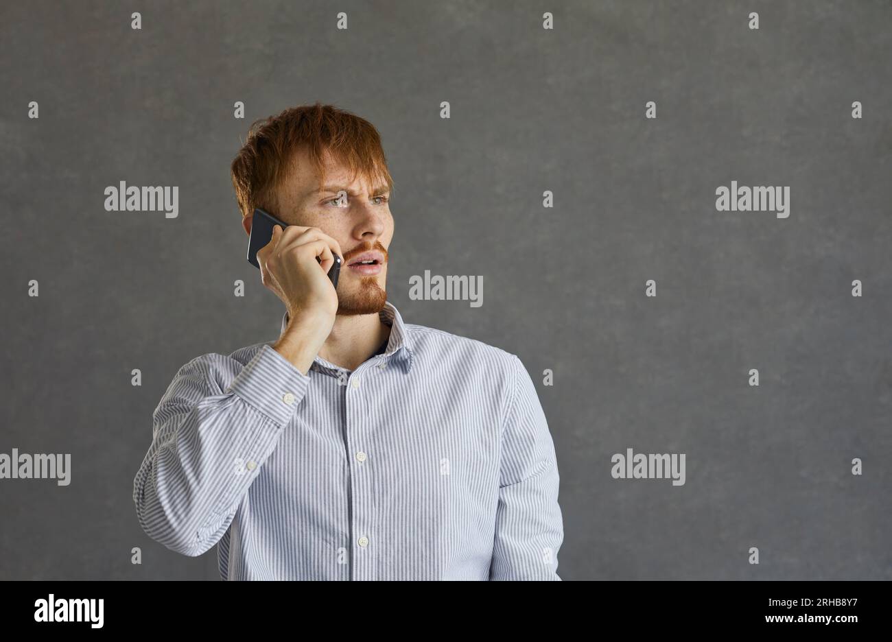 Un giovane che parla al telefono cellulare con un'espressione del volto arrabbiata e travagliata Foto Stock