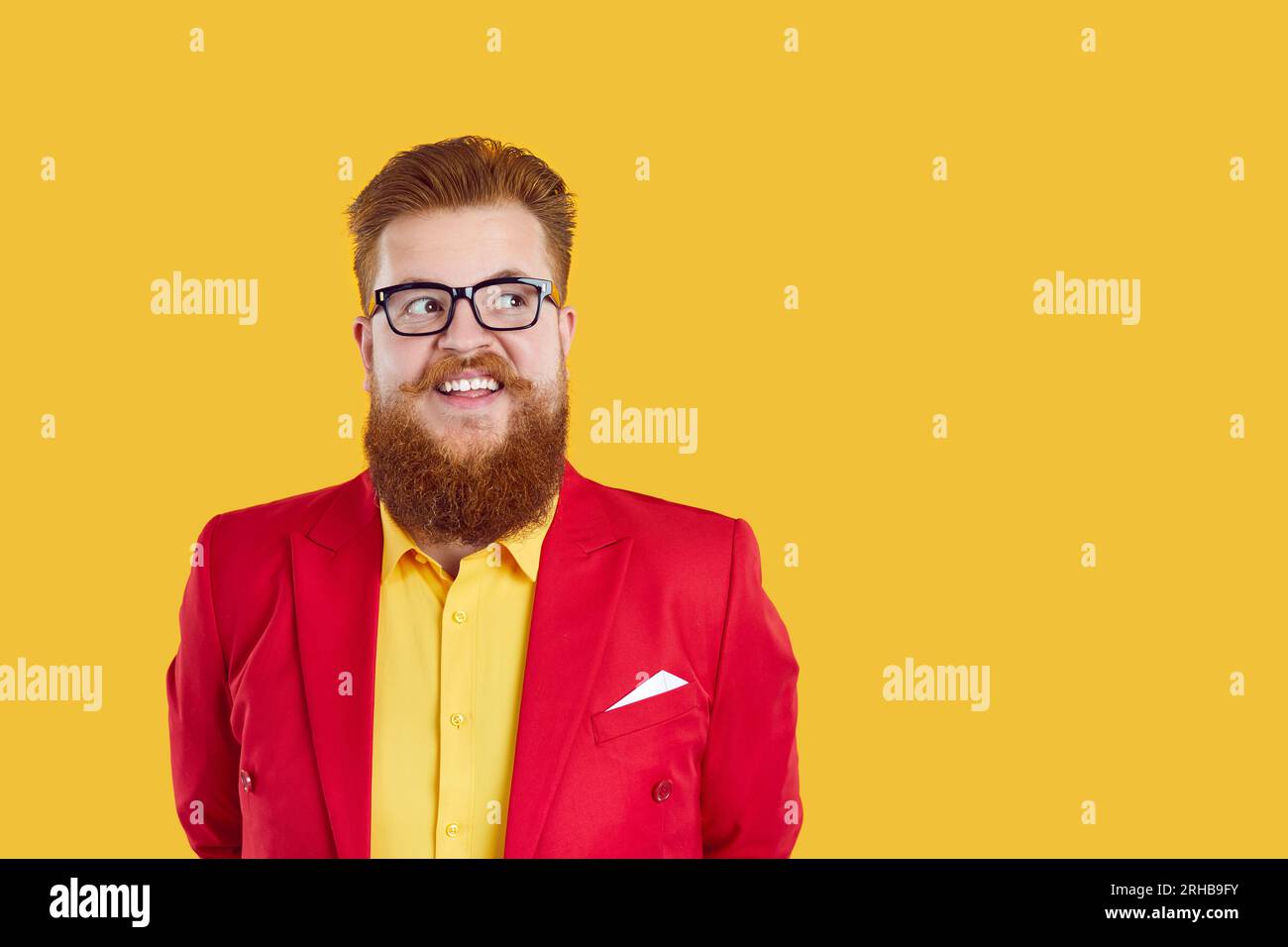 Un paffuto dalla barba rossa con occhiali e un vestito stravagante che guarda da parte sullo spazio per le copie su sfondo giallo. Foto Stock