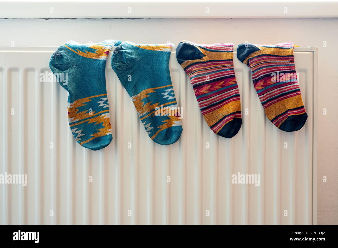 Due paia di calze colorate sul radiatore bianco dopo il lavaggio. Alloggi, economia, tema domestico Foto Stock