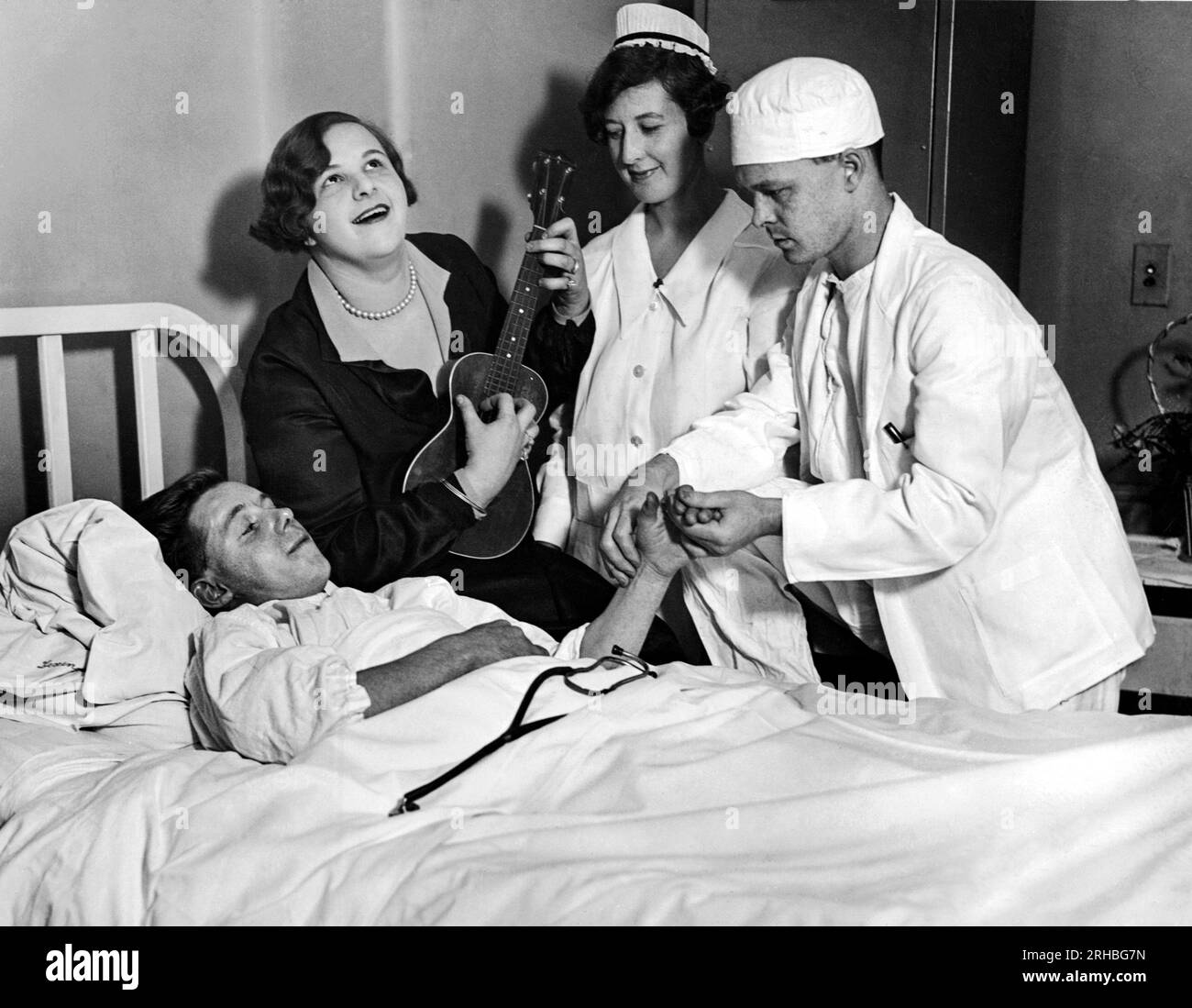 New York, New York: 7 ottobre 1926 la diciannovenne Kate Smith della Honeymoon Lane Theater Company fornisce una sincopazione melodiosa come Dr. O. Dannenbrink del Lexigton Hospital esegue un intervento chirurgico su un paziente senza etere. Foto Stock