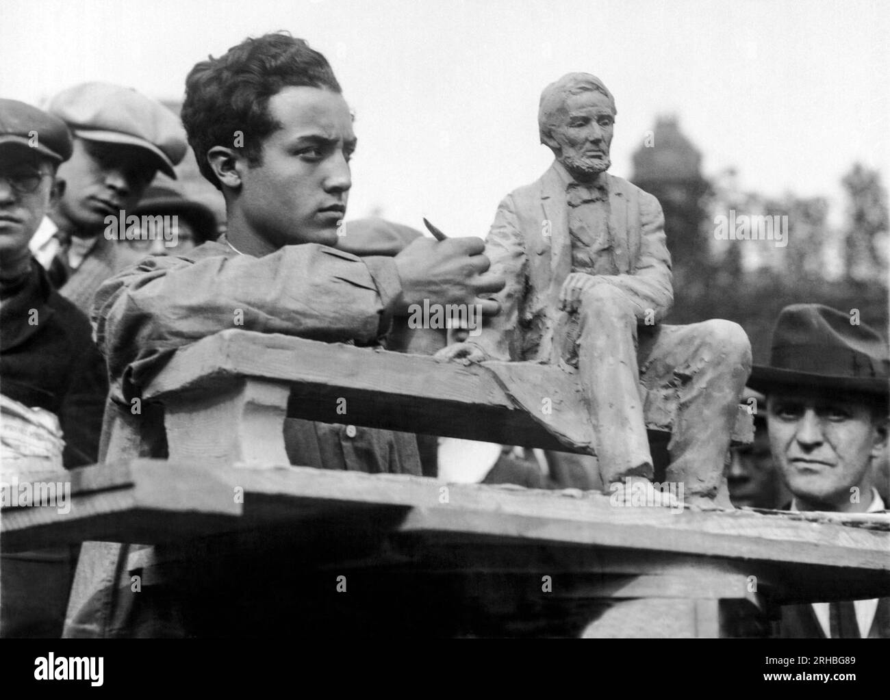 Newark, New Jersey: 11 novembre 1924 Isamu Noguchi, diciannovenne allievo della New Leonardo da Vince Art School di New York. Qui sta modellando una copia in miniatura del Lincoln Monument mentre i passanti guardano con meraviglia e ammirazione. Foto Stock
