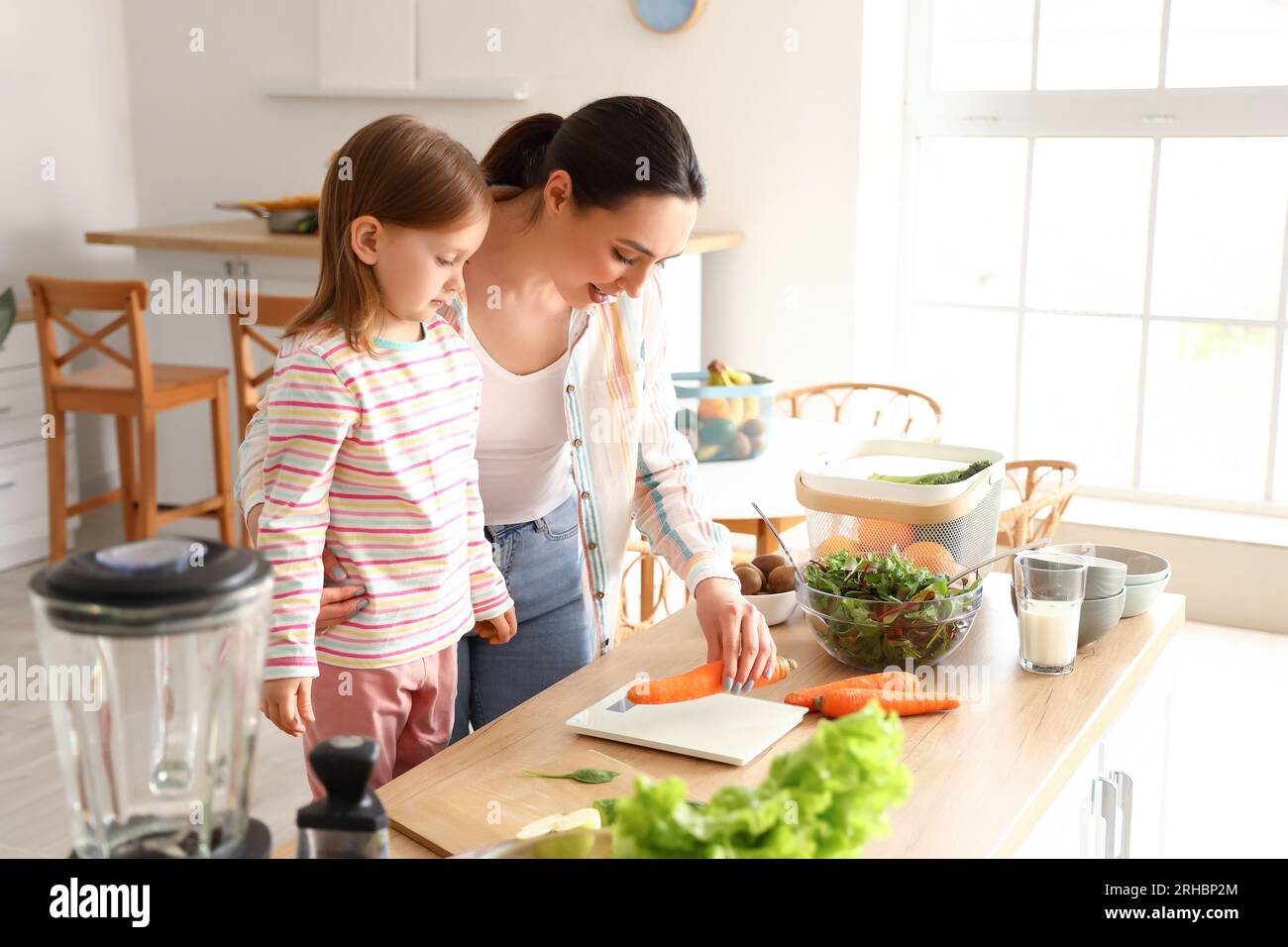 Bambina con sua madre che prepara insalata sana in cucina Foto Stock