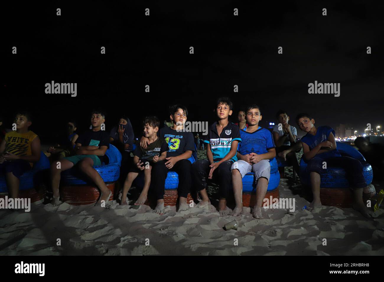 Gaza. 10 agosto 2023. I palestinesi guardano un film su un grande schermo installato su una spiaggia nella città di Gaza, il 10 agosto 2023. Entusiasti e grati per questa iniziativa di creare un cinema all'aperto gratuito, decine di spettatori di cinema locali di varie età si riunirono davanti al grande schermo dopo il tramonto. Guardavano film di diversi generi seduti su sedie convertite da pneumatici rotti riciclati. Crediti: Rizek Abdeljawad/Xinhua/Alamy Live News Foto Stock