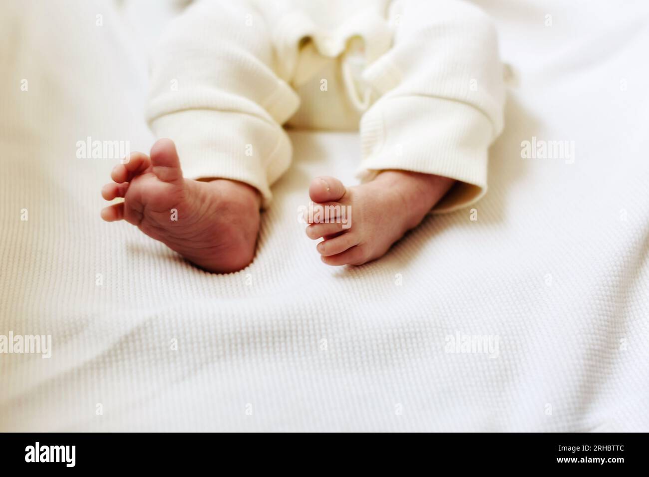 Primo piano dei piedi di un bambino in un babygro Foto Stock