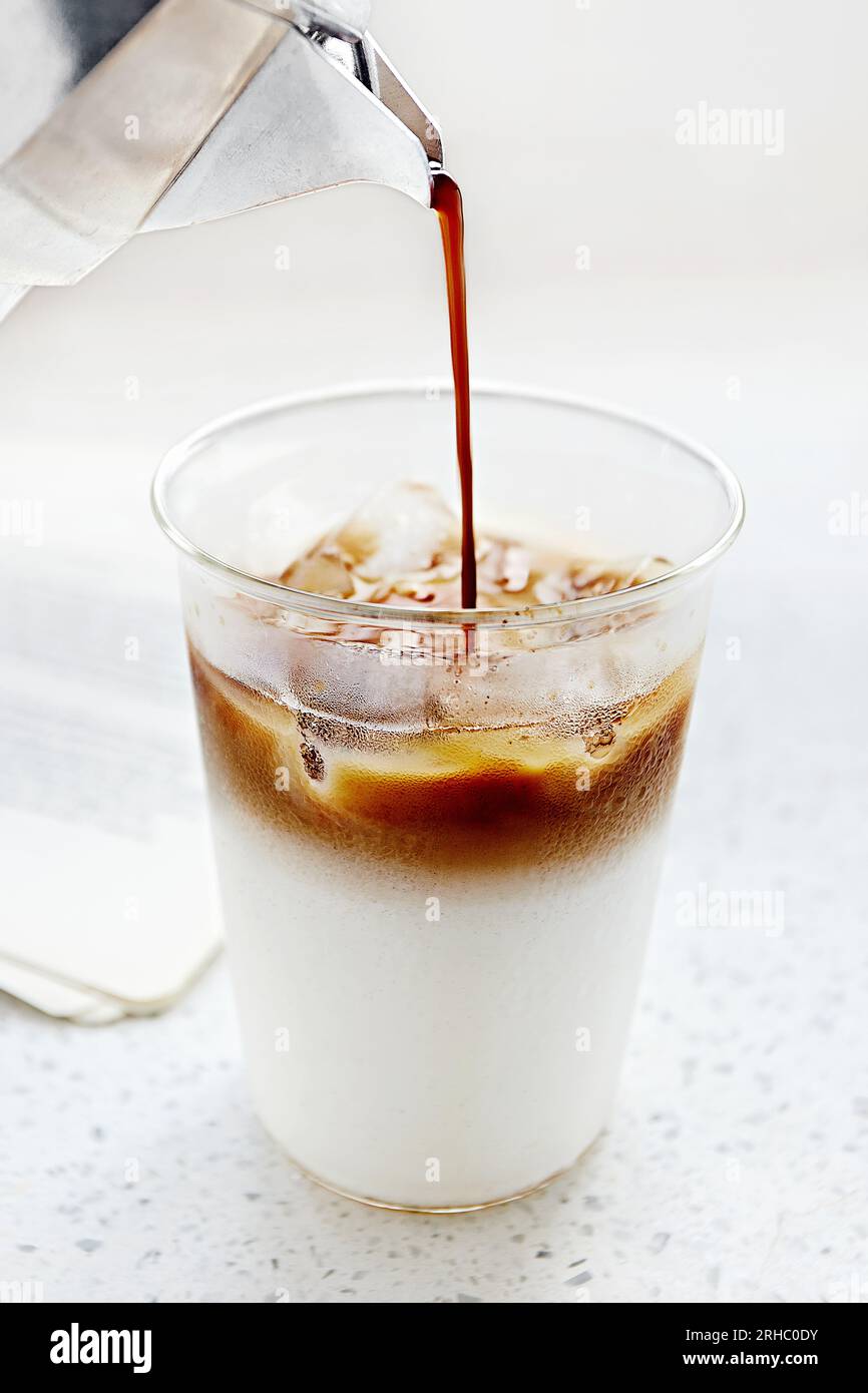 Primo piano del caffè versato in un bicchiere di latte Foto Stock