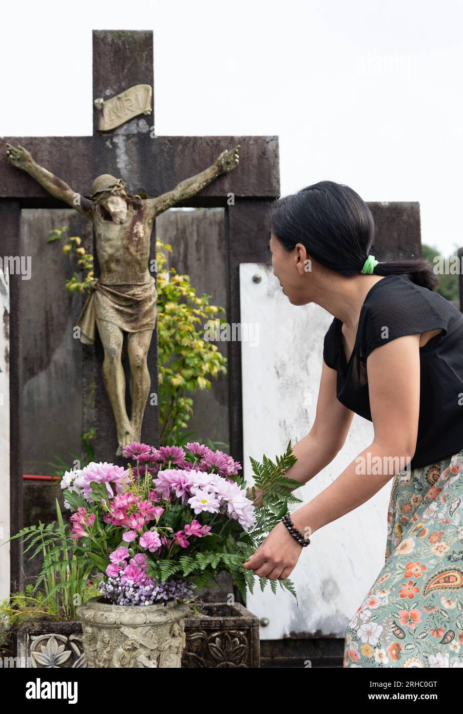 donna che mette fiori nel cimitero Foto Stock