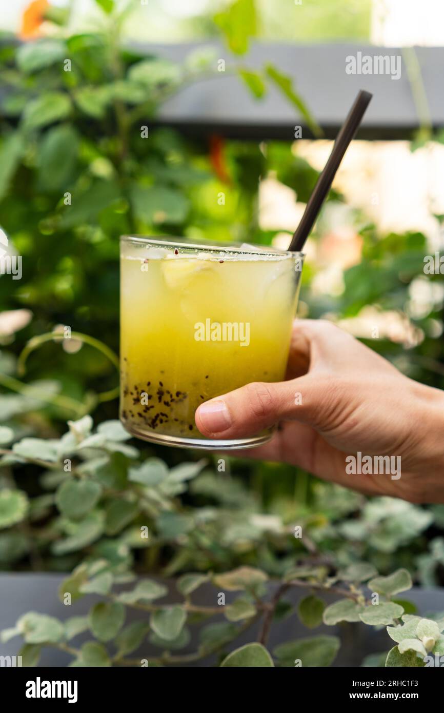 Primo piano di una donna all'aperto che tiene un kiwi verde e un cocktail di basilico Foto Stock