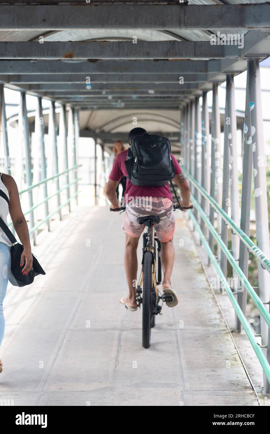 Salvador, Bahia, Brasile - 11 agosto 2023: Un ciclista che attraversa la passerella pedonale con la sua bicicletta sull'Avenida Tancredo Neves a Salvador, Bahia, Foto Stock