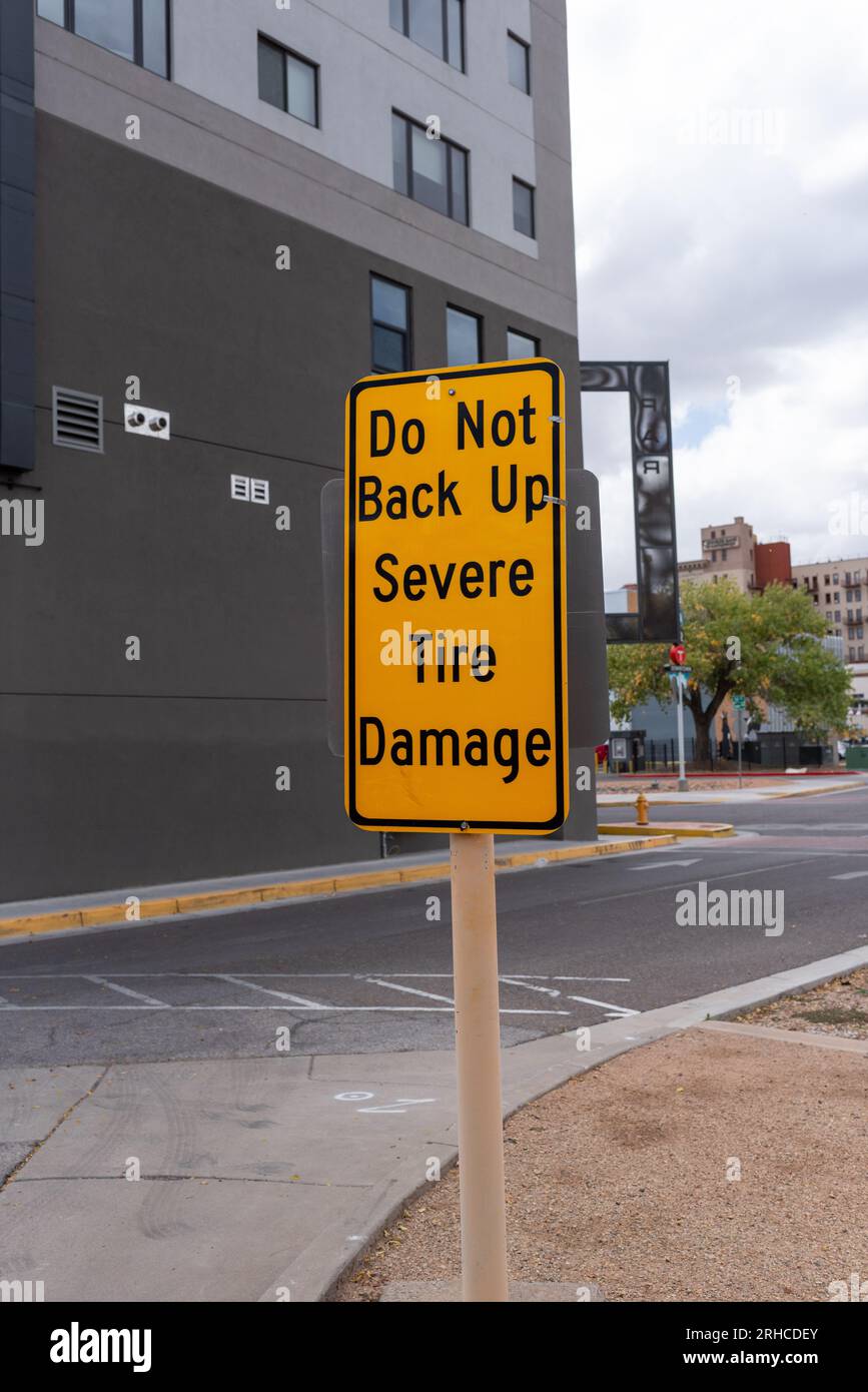 Un cartello di avvertenza giallo brillante apposto all'uscita di un parcheggio indica: Non eseguire il backup di gravi danni agli pneumatici. Foto Stock