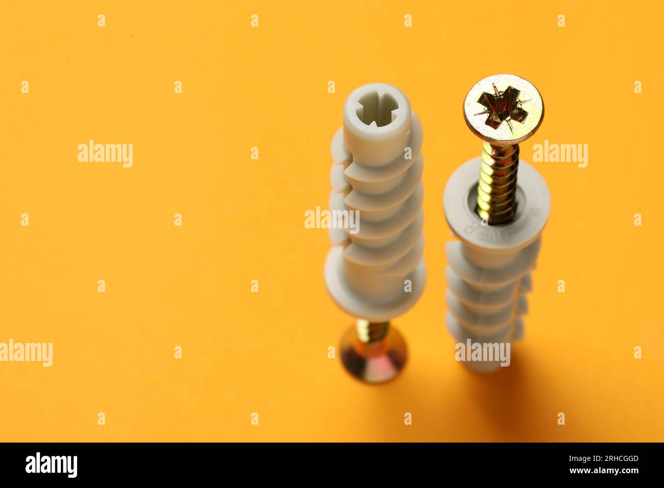 Viti metalliche con perni su sfondo arancione. Spazio per il testo Foto Stock