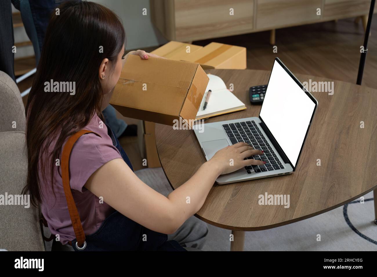 Giovane donna d'affari che lavora online e-commerce a casa. Una giovane donna venditrice prepara una scatola di prodotti da consegnare al cliente Foto Stock
