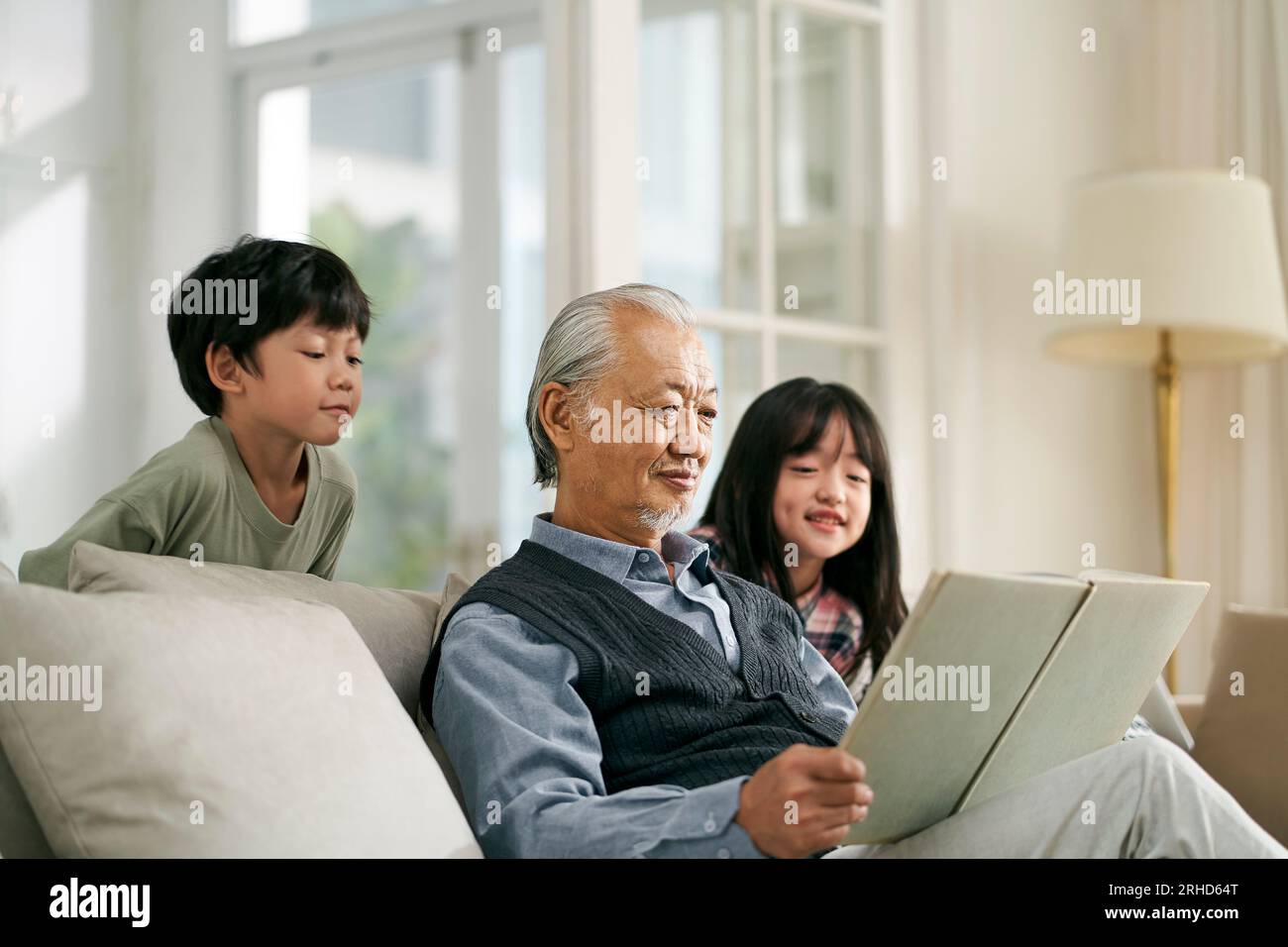 nonno asiatico che si diverte a raccontare la storia a carini nipoti e nipoti Foto Stock