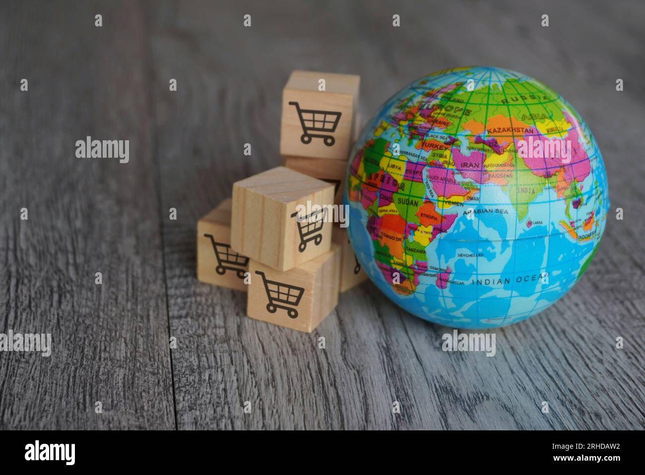 Immagine ravvicinata del globo e dei cubi di legno con l'icona del carrello della spesa. Retail globale, concetto di business internazionale. Foto Stock