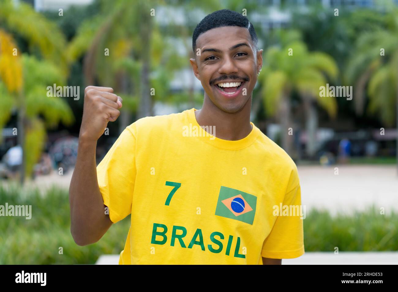 Felice giovane brasiliano con maglia da calcio gialla all'aperto a San Paolo Foto Stock