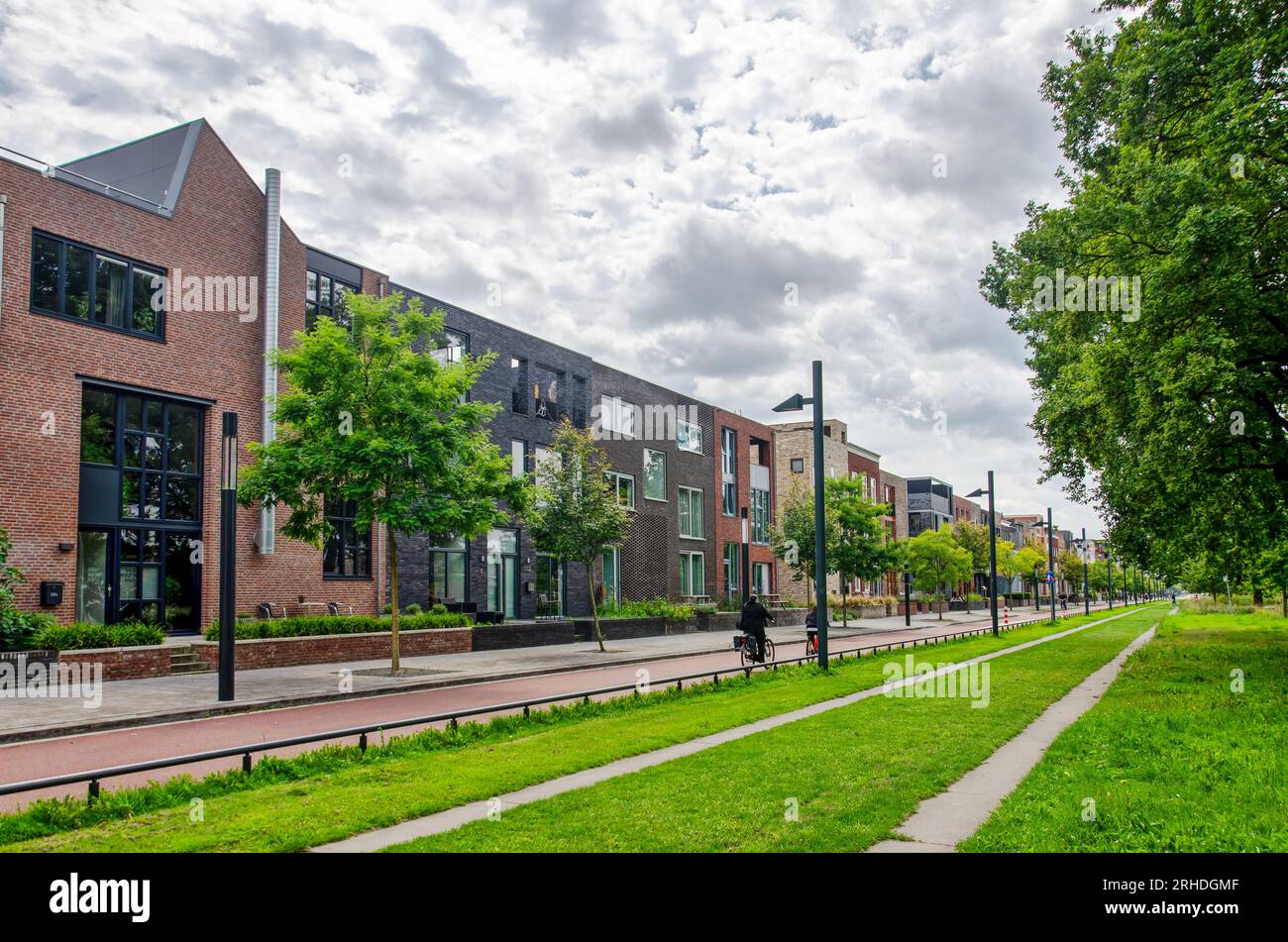 Enschede, Paesi Bassi, 9 agosto 2023: Lunga facciata con edifici residenziali lungo l'asse centrale nel quartiere ricostruito di Roombeek Foto Stock