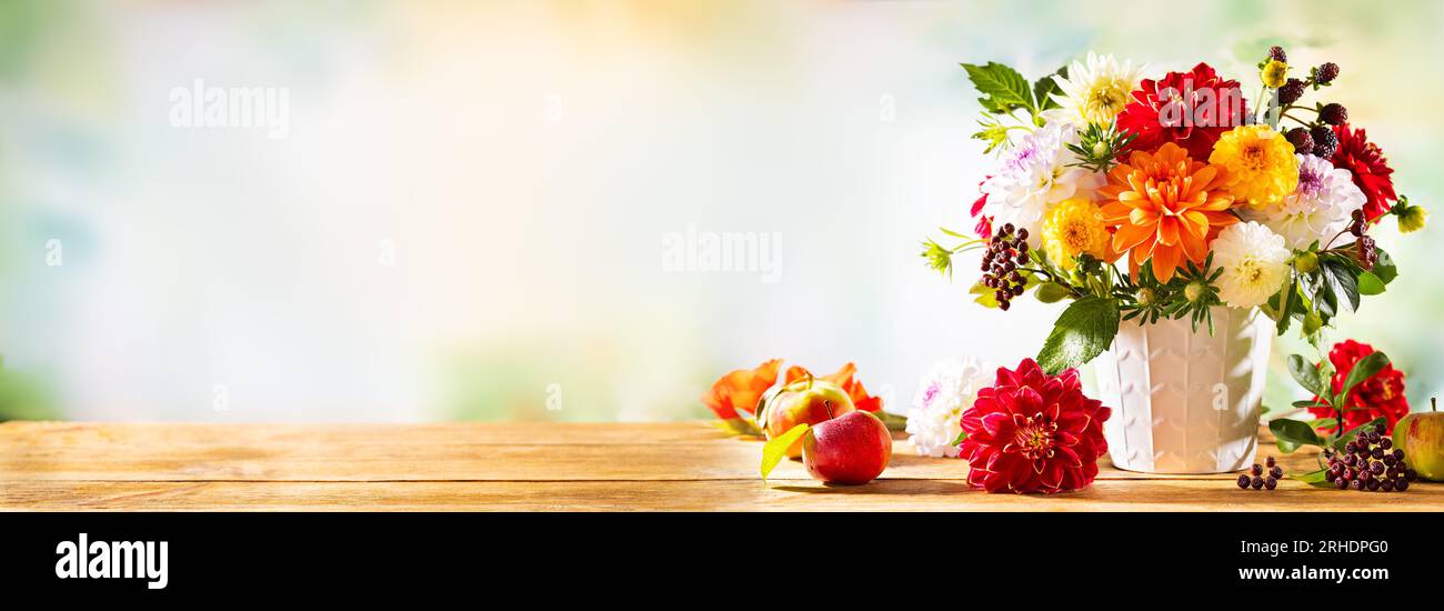 Natura morta autunnale con fiori da giardino. Bellissimo bouquet autunnale in vaso, mele e frutti di bosco su un tavolo di legno. dahlia colorata e crisantemo. Foto Stock