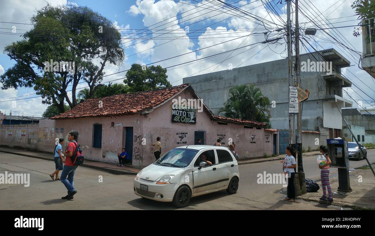 Foto che mostra la vita pubblica in una strada della città di Calabozo in Venezuela, raffigurata che mostra alcuni vecchi edifici, vecchie auto e persone. Foto Stock