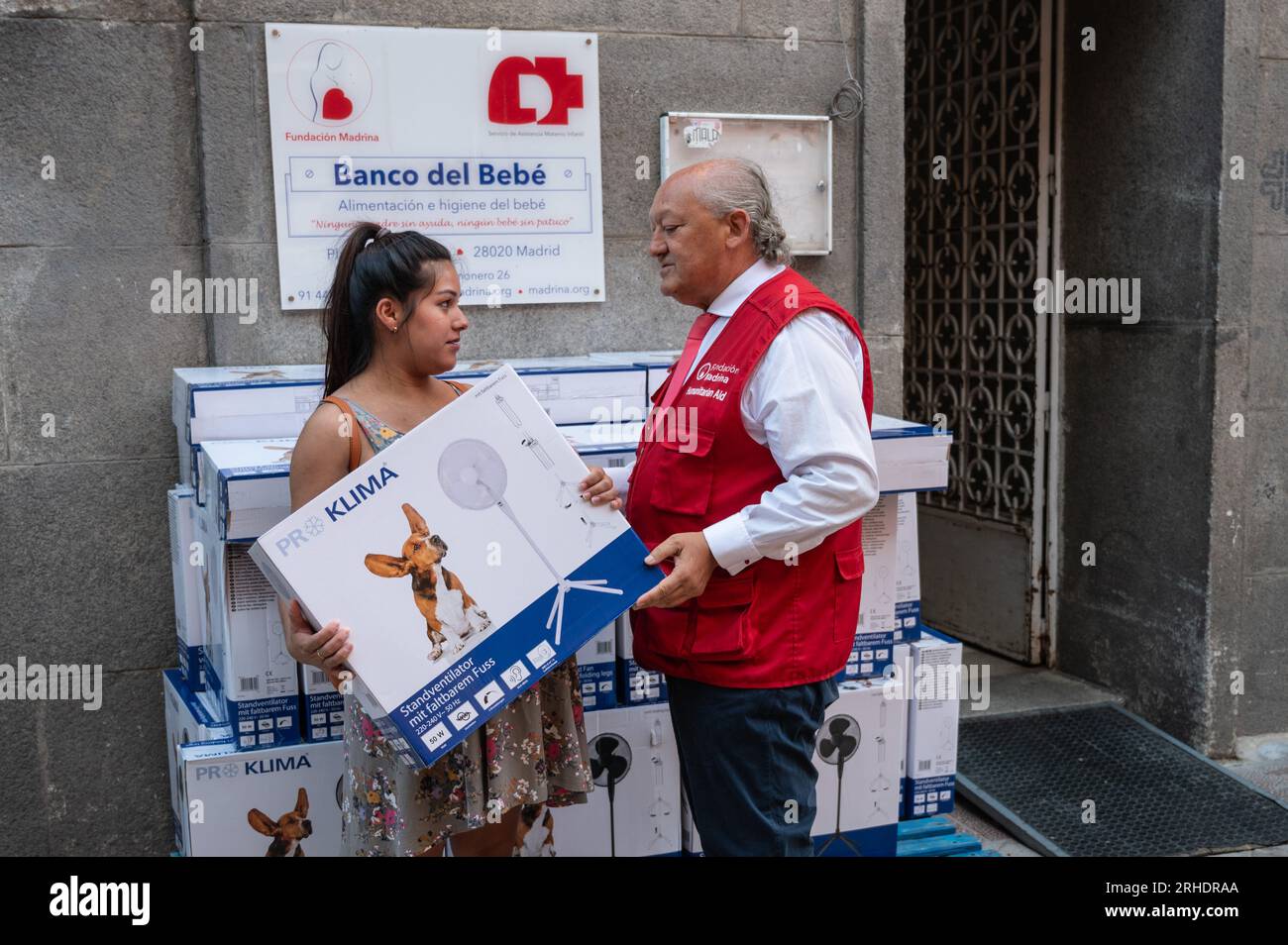 Madrid, Spagna. 16 agosto 2023. Conrado Gimenez, fondatore e presidente di Fundacion Madrina, consegna un fan a una donna a rischio di esclusione sociale. Fundacion Madrina fornisce fan a bambini e madri vulnerabili, per far fronte alle alte temperature e alle onde di calore durante l'estate, oltre a fornire cibo e vestiti. La Fundacion Madrina è un ente di assistenza benefica dedicato all'assistenza e all'aiuto di gruppi a rischio di esclusione o emarginazione nel campo dell'infanzia, delle donne e della maternità. Crediti: Marcos del Mazo/Alamy Live News Foto Stock