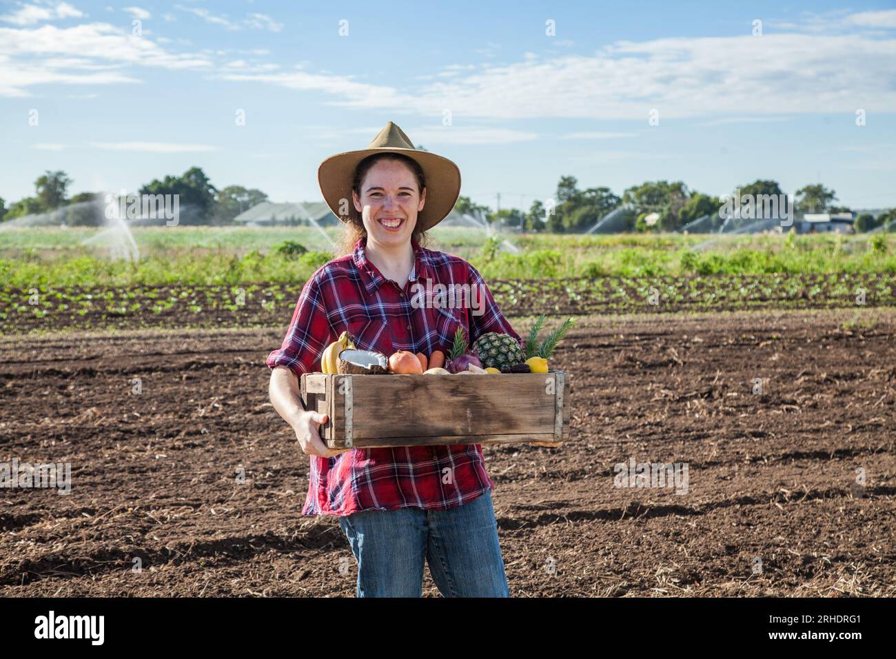 Giovane australiano che tiene una scatola di frutta fresca e verdura all'aperto in una fattoria Foto Stock