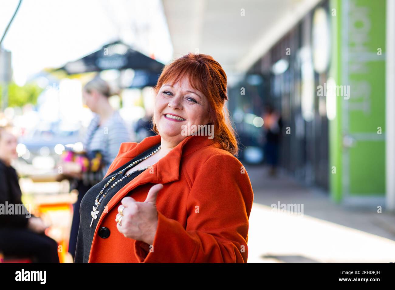 Ritratto di una donna di mezza età con testa rossa vicino al caffè sulla strada della città australiana Foto Stock