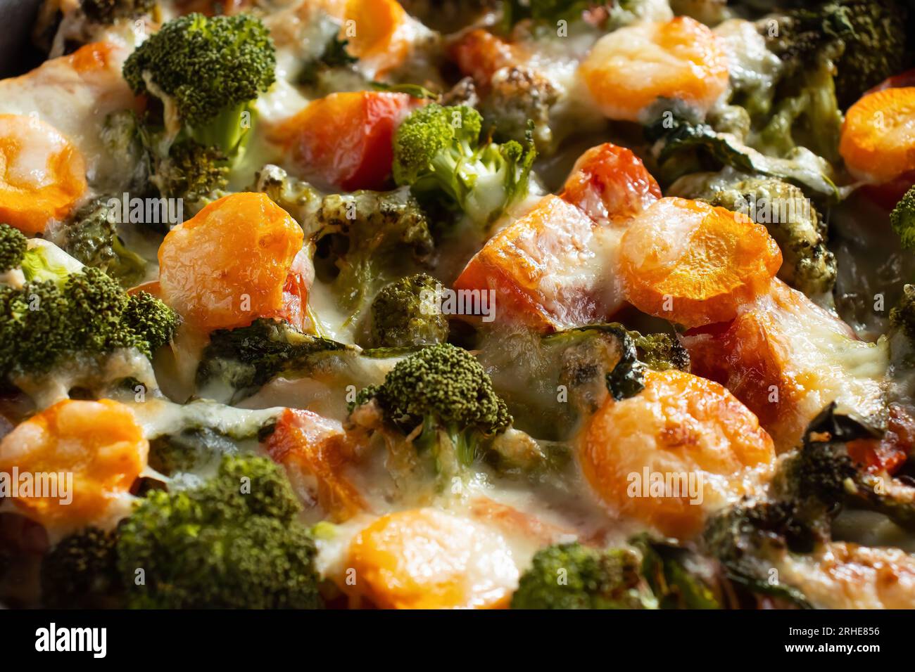 Gratinate con broccoli, carote e formaggio cotto in forno su un tavolo di legno scuro, da vicino. Foto Stock