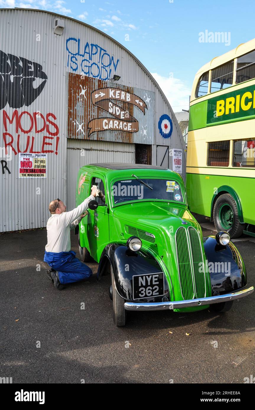 Ricostruzione di una scena di garage degli anni '1950 o '1960 con la pulizia di un popolare furgone Ford del 1953. Graffiti d'epoca dipinti a parete. Regola mod. Clapton e' Dio Foto Stock