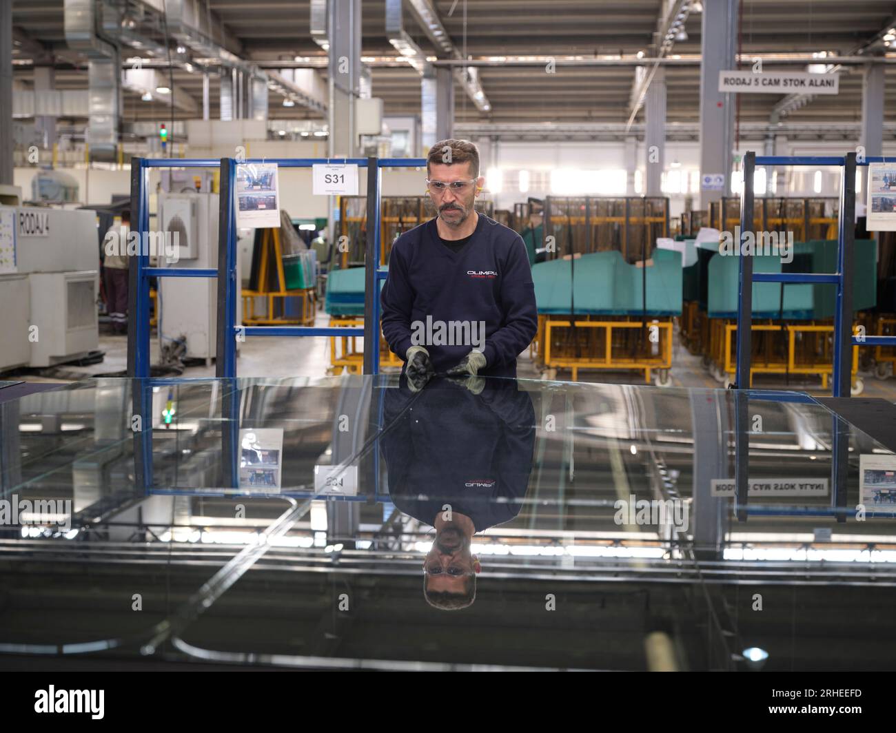 Fabbrica per la produzione di finestrini e parabrezza per auto. Lavoratore manuale che assembla finestre in PVC e finestrini per auto. Lavoratori che confezionano fogli di vetro in magazzino Foto Stock