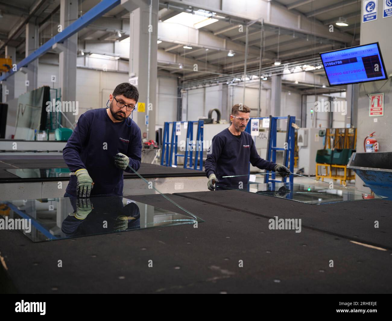 Fabbrica per la produzione di finestrini e parabrezza per auto. Lavoratore manuale che assembla finestre in PVC e finestrini per auto. Lavoratori che confezionano fogli di vetro in magazzino Foto Stock